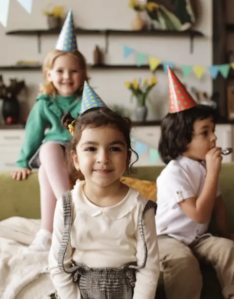 Crianças com chapéu de festa num aniversário