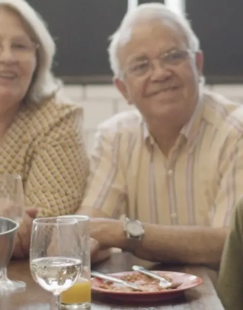 Casal de idosos sorrindo à mesa